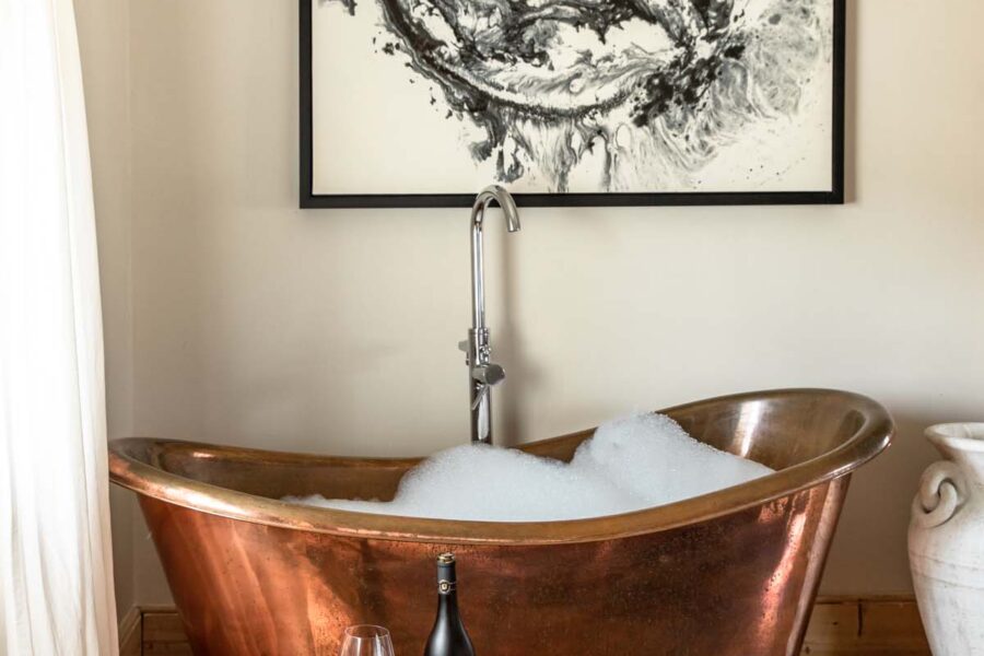 copper roll top bath with glass of red wine