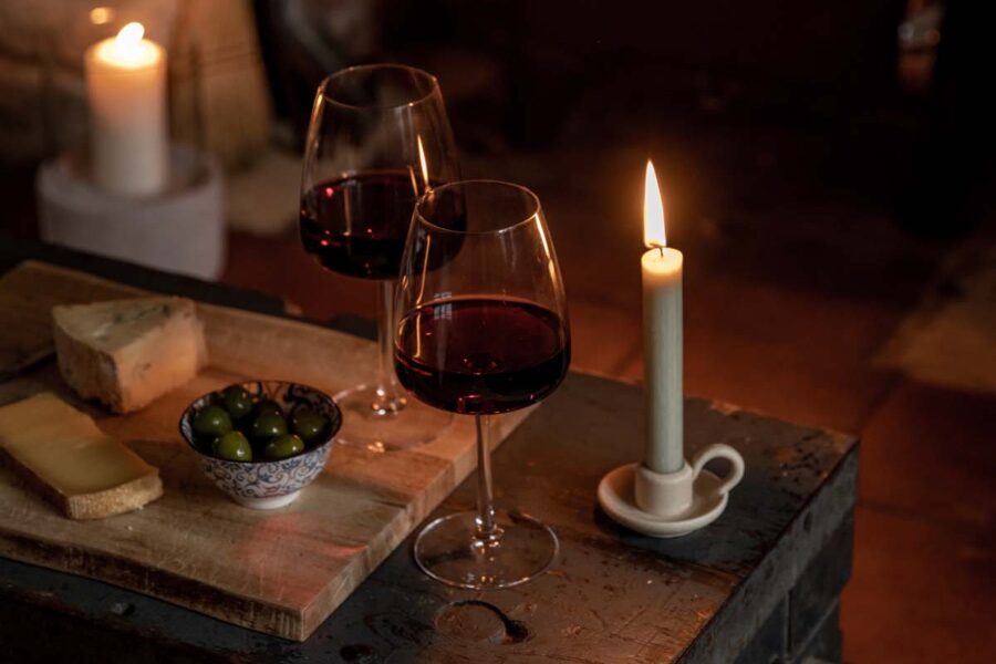 Two glasses of red wine and a candle by the fireplace