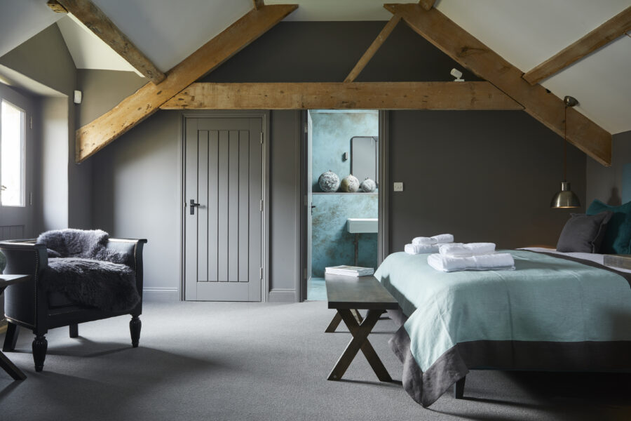 Double bed with blue throw and ensuite bathroom