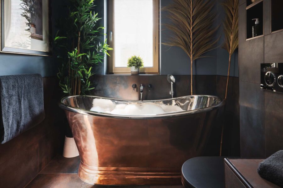 Roll top copper bath tub full of bubbles
