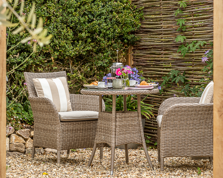 Wicker table and chairs with flowers and breakfast set up