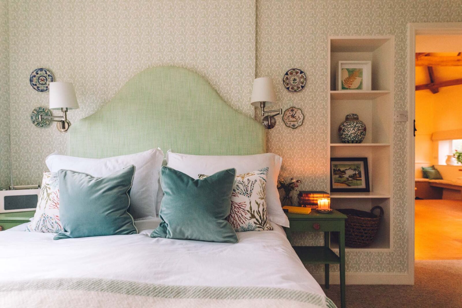 Bedroom with a green headboard and velvet cushions