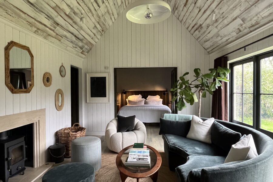 Bedroom opening up onto living room with velvet sofas and wooden ceilings