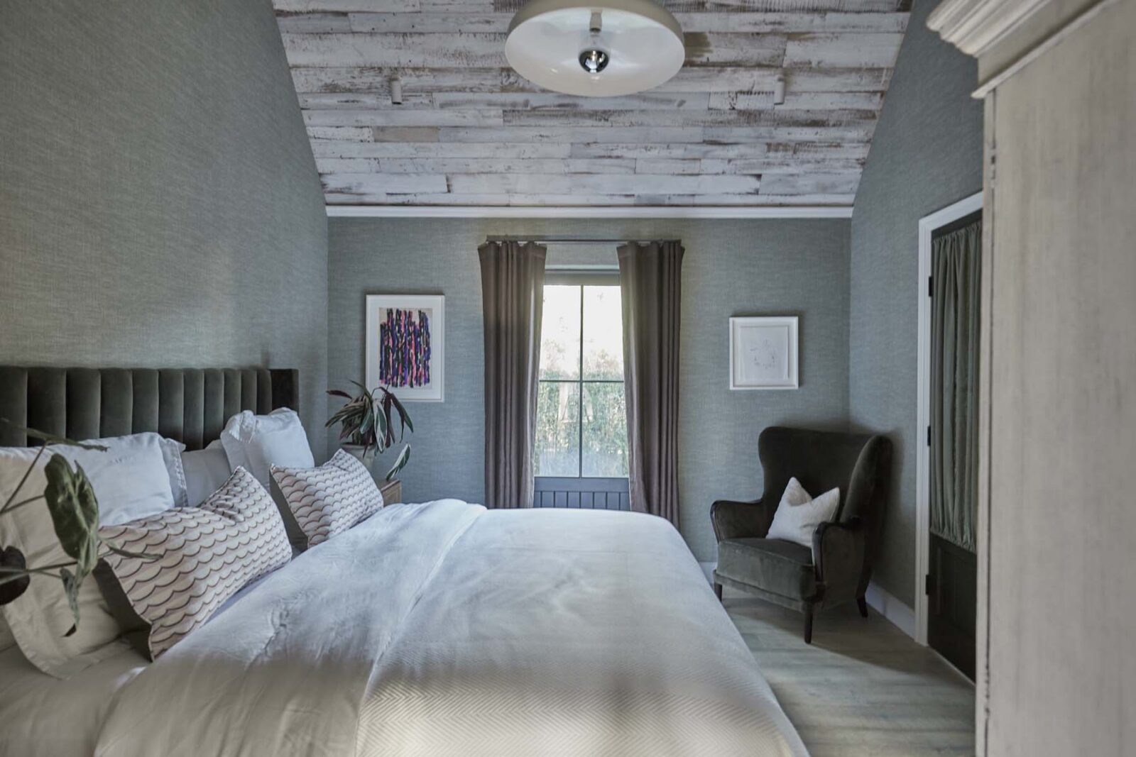 Bed in bedroom with armchair and window