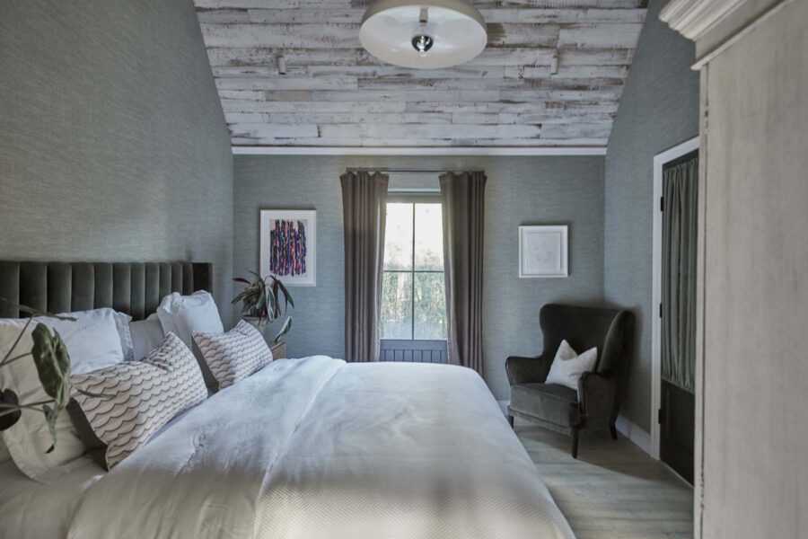 Bed in bedroom with armchair and window