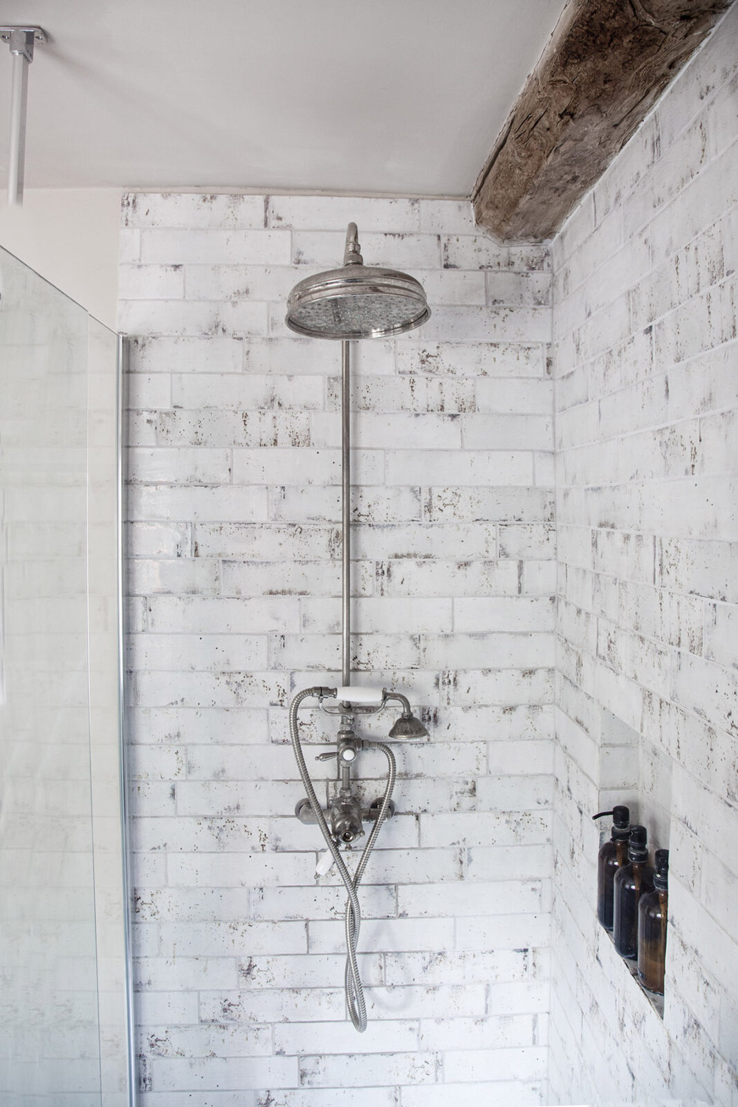 shower with white wash brick walls