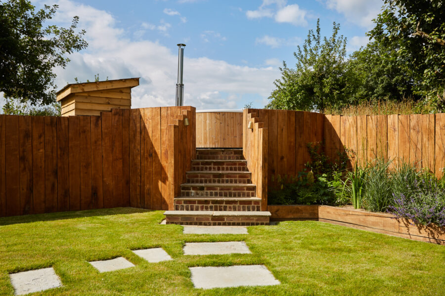 A wooden outdoor hot tub on a sunny day with blue skies
