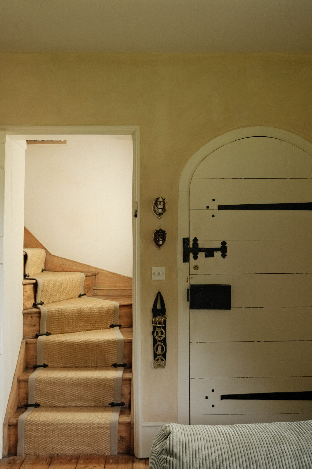 View of the staircase from the living room with the traditional old front door next too it.